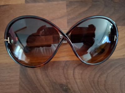 des lunettes de soleil posées sur une table en bois, avec une paire de chaussures en arrière-plan