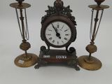 a clock that is sitting on a table with three candles