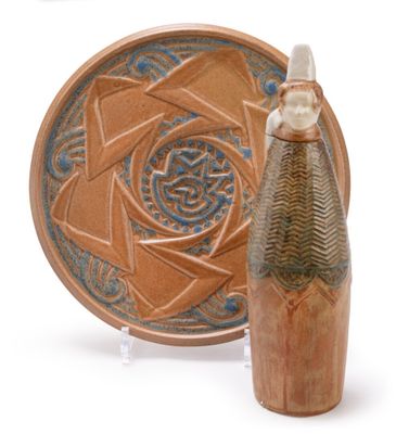 a small vase next to a plate with a design on it