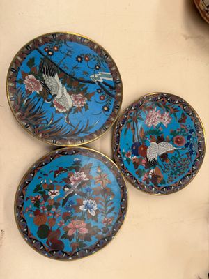 trois assiettes décoratives ornées d'oiseaux et de fleurs, posées sur une table