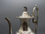 a silver tea pot with a bird on top of it