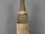 an old bottle of wine sitting on top of a glass table