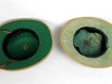two green hats sitting on top of each other on a white surface