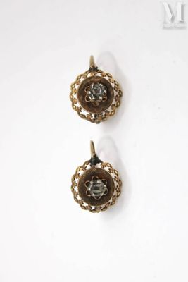 two gold tone earrings on a white surface with a white background