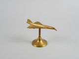 figurine d'avion en laiton posée sur un socle, sur fond blanc