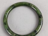 a close up of a green bracelet on a white surface