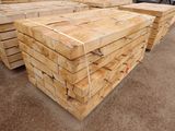 plusieurs piles de planches de bois empilées les unes sur les autres dans un parking