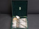 a set of silverware in a case with a spoon and spoon rest