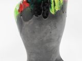 a black vase with a green, yellow, and red design on it