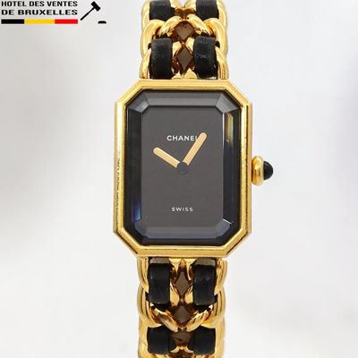 une montre noire et dorée, entourée d'une chaîne