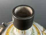 a close up of a vase with a cup on it