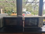 two microwaves sitting on a counter in front of a window