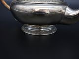 a silver tea pot on a table with a black background