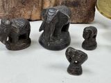 a small group of elephant figurines sitting next to a pile of coins