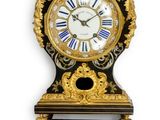 une image représentant une horloge noire et dorée accrochée à un mur blanc