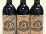 trois bouteilles de vin rouge posées l'une à côté de l'autre sur une surface blanche