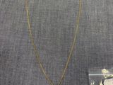 un collier en or orné d'une pièce, à côté d'un sac en plastique