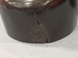 a black vase with a brown lid on a white table