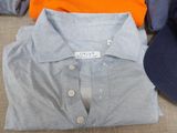 three shirts and a hat sitting on a couch