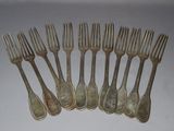 six forks are arranged in a row on a white surface
