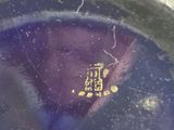 a close up of a purple vase with a yellow label