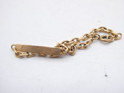 a close up of a gold chain bracelet with a tag on it