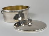 a silver container with a lid and a spoon on it