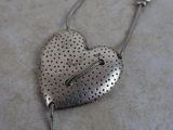 a silver heart shaped necklace on a table next to a pair of scissors