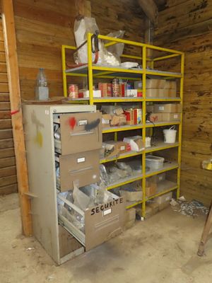 a refrigerator in the corner of a room with a shelf full of items