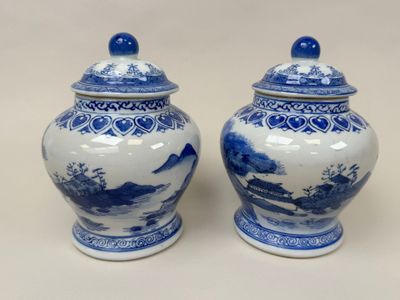 pair of blue and white vases with a landscape scene on them