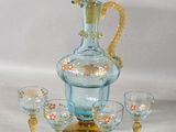 a blue glass decanter with a gold handle and four glasses