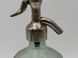 a green glass bottle with a metal stopper on it