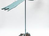 une photo d'une sculpture métallique représentant un oiseau posé sur un rocher