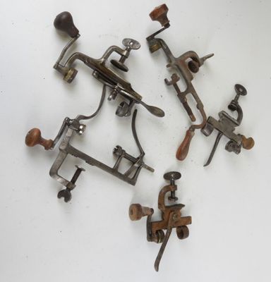 un ensemble de quatre anciennes pinces en métal et en bois posées sur une surface blanche