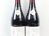 deux bouteilles de vin rouge posées l'une à côté de l'autre sur une surface blanche