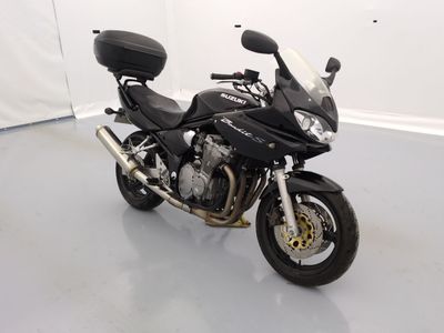 une moto noire garée dans une pièce aux murs blancs