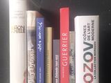 Plusieurs livres sont alignés sur une étagère devant un mur noir