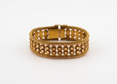 gros plan d'un bracelet en or sur une surface blanche