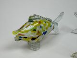 a glass fish figurine sitting on a table next to other glass figurines