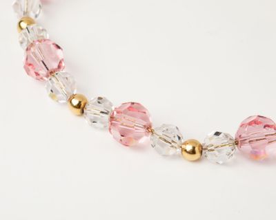 pink crystal and gold beaded necklace on a white background