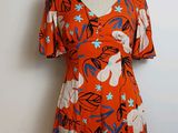une robe orange à fleurs bleues et blanches, présentée sur un mannequin