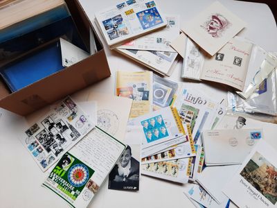 une boîte remplie de courrier posée sur une table, à côté d'une pile de cartes postales
