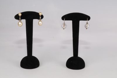 deux paires de boucles d'oreilles posées sur un présentoir noir, sur fond blanc