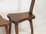 two wooden chairs sitting next to each other on a white surface