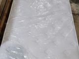 un matelas emballé dans du plastique, posé par terre