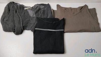 trois pulls sont alignés sur une table, avec un pull posé par-dessus