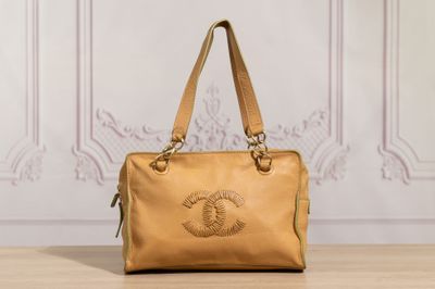 a brown purse sitting on top of a wooden table next to a wall