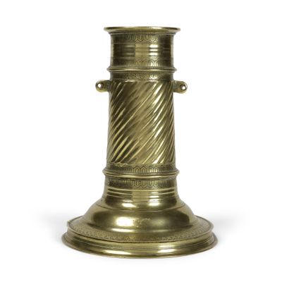 un vase en or posé sur une surface blanche