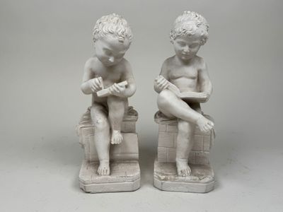 two figurines of children sitting on blocks