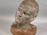 statue représentant la tête d'un homme, posée sur un socle en bois